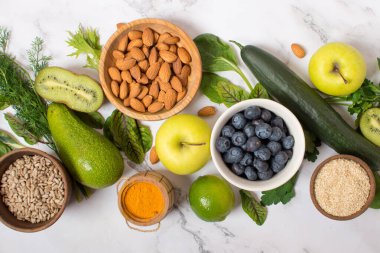 Healthy food clean food selection: fruits, vegetables, seeds, superfoods, cereals, leafy vegetable on gray concrete background