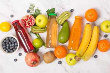 Gri masa üzerinde taze meyve suyu şişeleri, üst manzara. Meyveli bir bardak taze sağlıklı meyve suyu.