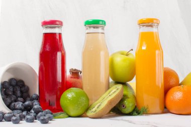 Taze Meyve Smoothie Kırmızı Yeşil Sarı Tropik Meyveler. Gri masa üzerinde taze meyve suyu şişeleri, üst görünüm