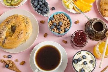 Pembe arka planda sağlıklı bir kahvaltı. Kahvaltı süzme peynir ve yoğurt, böğürtlen, müsli, meyve, avokado, kruvasan..