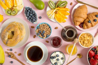 Pembe arka planda sağlıklı bir kahvaltı. Kahvaltı süzme peynir ve yoğurt, böğürtlen, müsli, meyve, avokado, kruvasan..
