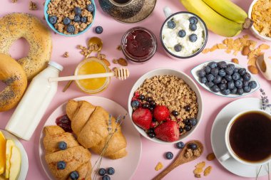 Masadaki sepetin içinde kahve ve kruvasanla kahvaltı. Fransız kahvaltısı. Pembe arka planda kruvasanlar