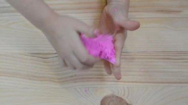 Yanlara pembe balçık geren küçük kız kireç düştü ve kız güldü. Çocuk elleri sümük oyuncağı oynuyor.