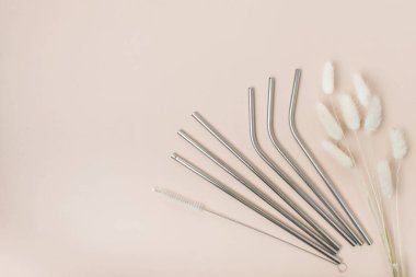 Beyaz arka planda sıralanmış altı metal içki pipetinin yüksek açılı görüntüsü