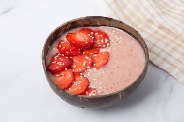 Chia tohumlu meyve suyu kasesi, müsli, çilek, muz dilimleri ve hindistan cevizi taneleri, masa üstü manzaralı. Sağlıklı kahvaltı kavramı