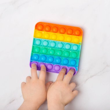 Ellerle oynamak için duyusal oyuncağı kullan. Gökkuşağı Boş bir fotokopi arkaplanındaki oyuncağı oynat