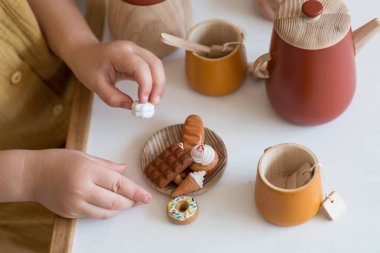 Çocuk mutfağında oynamak, çocuk çay seti, polimer tatlılar. Beyaz arka planda minyatür sahte pastalar ve çörekler. Oyuncak bebek evi minyatürü, polimer kil oyuncak, plastik mankenler.