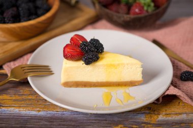 Klasik vanilyalı cheesecake (New York cheesecake) beyaz tabakta çilek sosu ve biberiye ve açık arkaplanlı