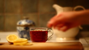 woman putting fresh lemon into black tea