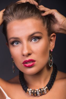 Şık makyaj ve aksesuarları karanlık bir arka plan üzerinde güzel bir esmer.