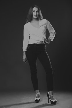 Şık giyimli genç iş kadını. Güzel genç iş kadını görüntüsü. Kız siyah pantolon ve karanlık bir arka plan üzerinde beyaz bir gömlek. Moda ve sosyal dergiler, Web siteleri için fotoğraf.