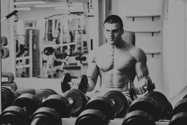 Um homem no ginásio. Homem faz exercícios com barra . — Fotografia de Stock