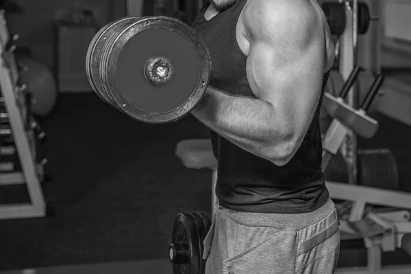 Um homem no ginásio. O homem faz exercícios com a campainha. Esporte, poder, halteres, tensão, exercício - o conceito de um estilo de vida são. Artigo sobre fitness e esportes . — Fotografia de Stock