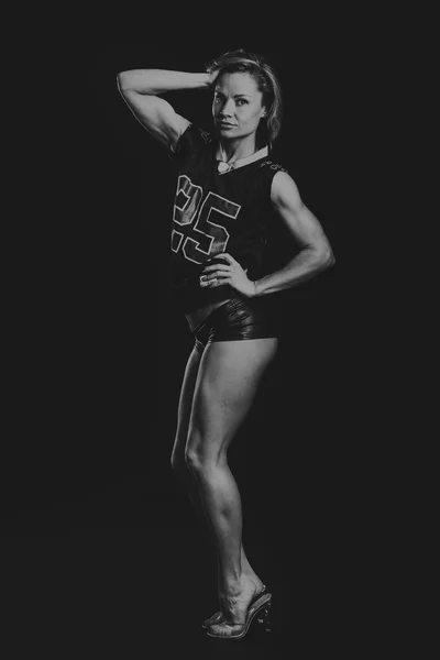 Menina sexy com uma figura perfeita, vestida com uma t-shirt jogador de futebol americano. Loira atlética sexy posando em um fundo preto. Menina muscular em um fundo preto . — Fotografia de Stock