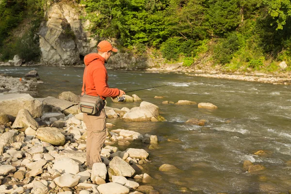 Pescatore su un fiume di montagna cattura pesci esotici. Pesca della trota nei fiumi Carpazi. Natura incontaminata delle montagne. Foto per la pesca e riviste naturali, manifesti e siti web . — Foto Stock