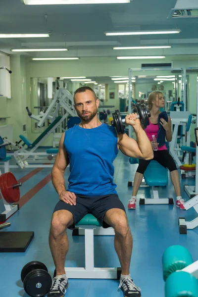 Strength training with dumbbells. Husky holds a large dumbbell in hand. Sport, bodybuilding, healthy lifestyle.