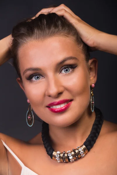 Een prachtige brunette met stijlvolle make-up en accessoires op een donkere achtergrond. — Stockfoto