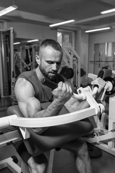 Sportovec lavice biceps na simulátoru v tělocvičně. Ruka svalové trénink na simulátoru. Napjaté svaly rukou pod zatížením. Fotografie pro sportovní časopisy, plakáty a webové stránky. — Stock fotografie