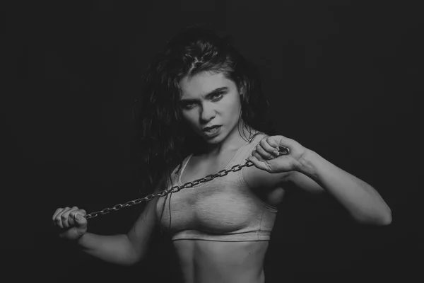 La ragazza sportiva con un pezzo di catena di metallo su sfondo scuro . — Foto Stock