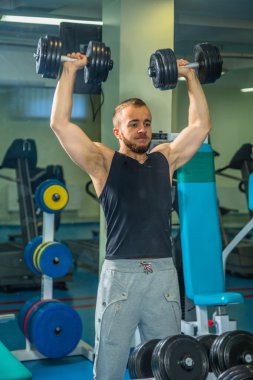 Adam jimnastik salonu. Egzersiz halter kılıyor. Spor, güç, halter, gerginlik, egzersiz - sağlıklı bir yaşam tarzı kavramı. Fitness ve spor hakkında makale.