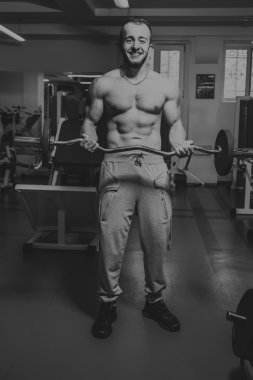 Kaslı adam spor salonunda ağırlık ile çalışma dışarı. Adam egzersizleri yapar.