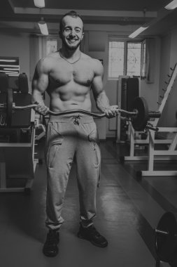 Kaslı adam spor salonunda ağırlık ile çalışma dışarı. Adam egzersizleri yapar.