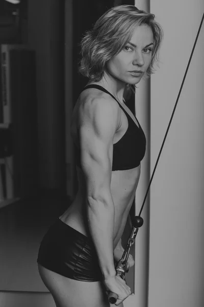 Sportos nő edzőteremben. Szép izmos alkalmas nő épület izmok gyakorlásában. Edzés az edzőteremben csinál szép szexi nő. — Stock Fotó