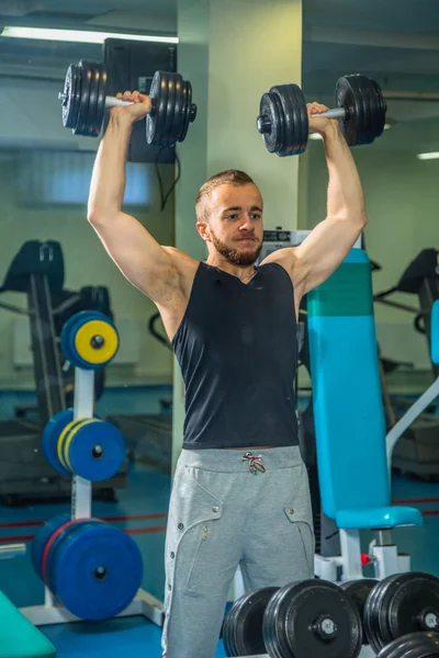 Man op de sportschool. Man maakt oefeningen halters. Sport, voeding, halters, spanning, oefening - het concept van een gezonde levensstijl. Artikel over fitness en sport. — Stockfoto