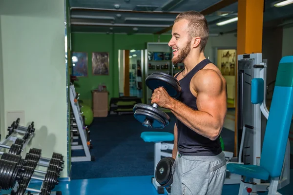 Man på gymmet. Man gör övningar hantlar. Sport, makt, hantlar, spänning, motion - konceptet med en hälsosam livsstil. Artikel om fitness och sport. — Stockfoto