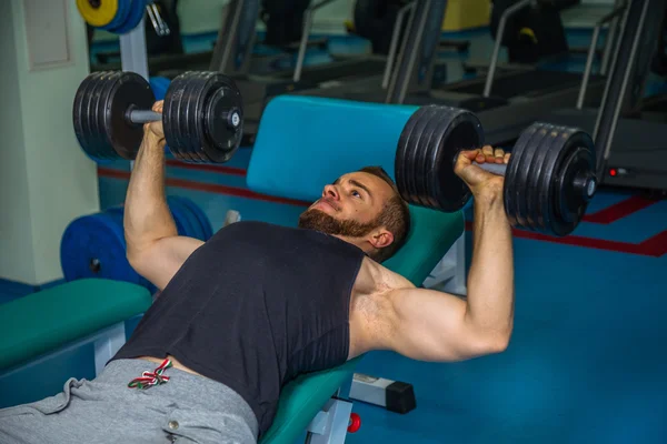 Man op de sportschool. Man maakt oefeningen halters. Sport, voeding, halters, spanning, oefening - het concept van een gezonde levensstijl. Artikel over fitness en sport. — Stockfoto