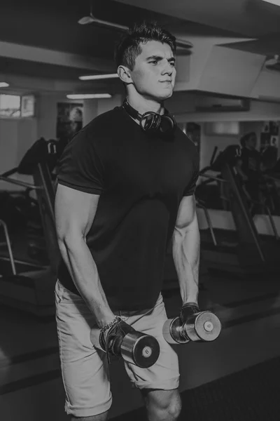Man at the gym. Man makes exercises dumbbells. Sport, power, dumbbells, tension, exercise - the concept of a healthy lifestyle. Article about fitness and sports. — Stock Photo, Image