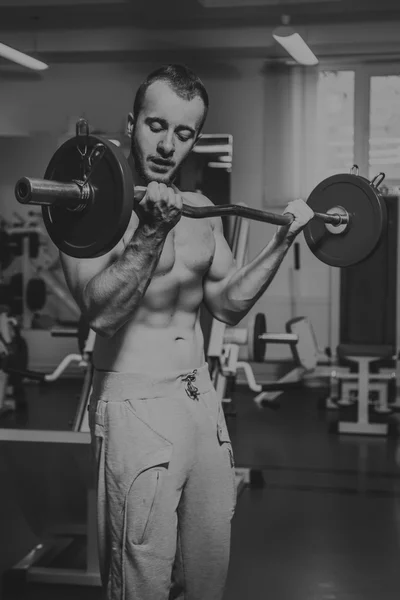 Muskularny mężczyzna pracy z ciężarami w siłowni. Człowiek czyni ćwiczenia. — Zdjęcie stockowe