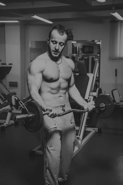 Hombre musculoso haciendo ejercicio con pesas en el gimnasio. El hombre hace ejercicios . — Foto de Stock