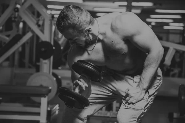 Hombre en el gimnasio. El hombre hace ejercicios de pesas. El deporte, el poder, las pesas, la tensión, el ejercicio - el concepto de un estilo de vida saludable. Artículo sobre fitness y deportes . — Foto de Stock