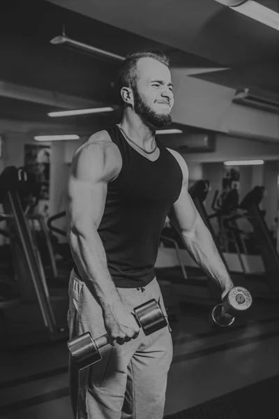 Hombre en el gimnasio. El hombre hace ejercicios de pesas. El deporte, el poder, las pesas, la tensión, el ejercicio - el concepto de un estilo de vida saludable. Artículo sobre fitness y deportes . — Foto de Stock