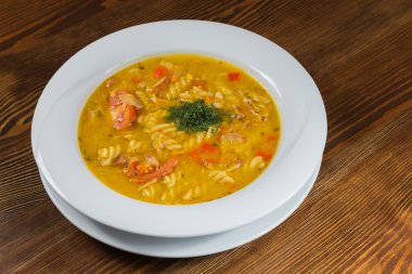 Çorba, sebze ve otlar beyaz plaka.