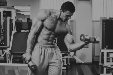 Vücut geliştirmeci yapar egzersiz jimnastik salonu dumbbells ile.