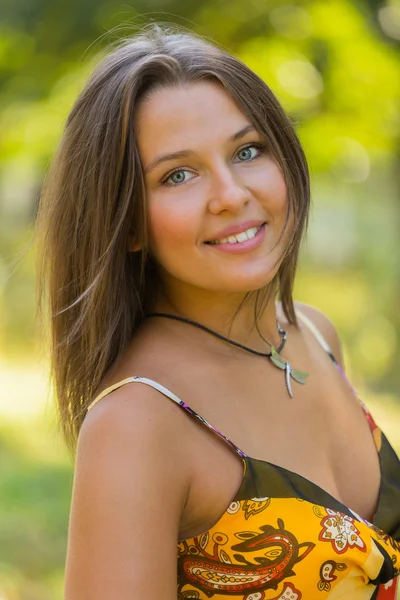 Una chica joven y atractiva en hermoso vestido de verano en medio de prados soleados . — Foto de Stock