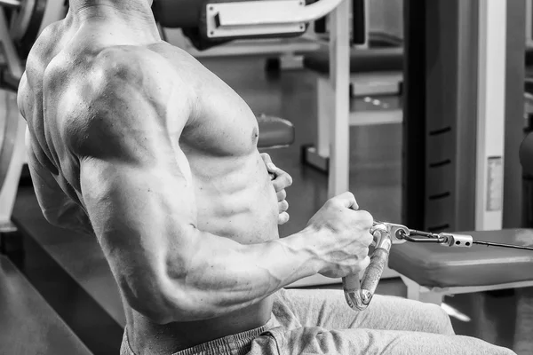 Homem musculoso forte fazendo exercícios no ginásio. Corpo bonito em uma foto em preto e branco. Estilo de vida saudável . — Fotografia de Stock