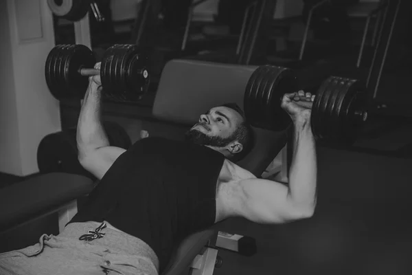 Hombre en el gimnasio. El hombre hace ejercicios de pesas. El deporte, el poder, las pesas, la tensión, el ejercicio - el concepto de un estilo de vida saludable. Artículo sobre fitness y deportes . — Foto de Stock