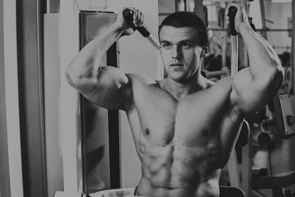 Starker muskulöser Mann bei Übungen im Fitnessstudio. schöner Körper auf einem Schwarz-Weiß-Foto. Gesunder Lebensstil. — Stockfoto