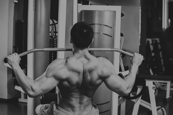 強い筋肉の男がジムで演習を行います。美しい体に黒と白の写真。健康的なライフ スタイル. — ストック写真