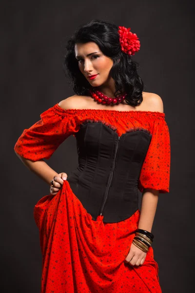 暗い背景に赤と黒のドレスで美しい若い女性の肖像画. — ストック写真