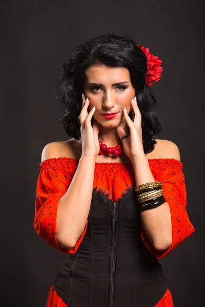 Retrato de uma bela jovem mulher em vestido vermelho e preto em um fundo escuro . — Fotografia de Stock