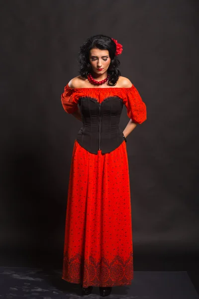 暗い背景に赤と黒のドレスで美しい若い女性の肖像画. — ストック写真