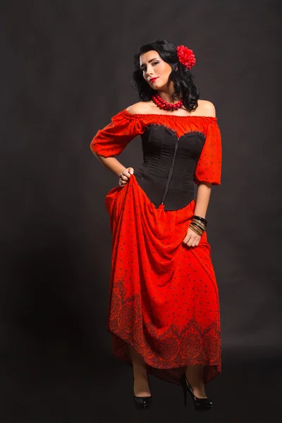Karanlık bir arka plan üzerinde kırmızı ve siyah elbiseli güzel bir genç kadın portresi. — Stok fotoğraf