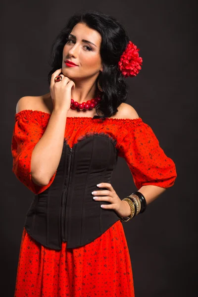 Porträt einer schönen jungen Frau in rotem und schwarzem Kleid auf dunklem Hintergrund. — Stockfoto
