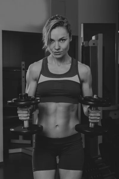 Sport blonde. Beautiful strong girl. Bodyfitness, women's fitness. Woman doing exercises at the gym. Beauty, health, and sports.Bodybuilder young adult sexy girl