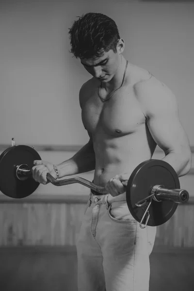 Der Prozess der körperlichen Bewegung mit Hanteln. Der Mann ist im Fitnessstudio beschäftigt. Training im Fitnessstudio. Gesunder Lebensstil. Foto im kreativen Bereich. — Stockfoto