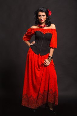 Karanlık bir arka plan üzerinde kırmızı ve siyah elbiseli güzel bir genç kadın portresi.